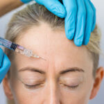 Doctor makes the rejuvenating facial injections for smoothing woman's forehead skin